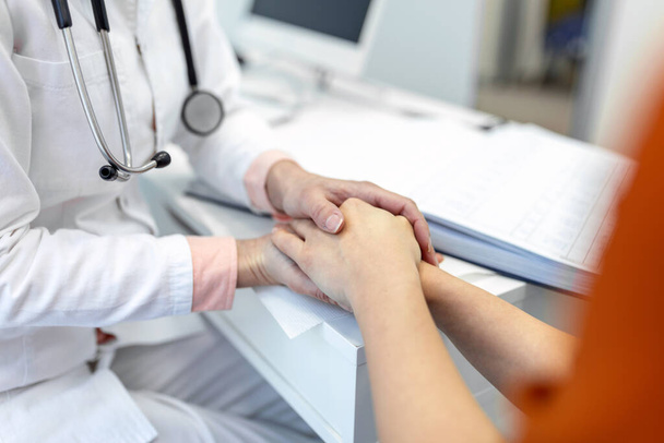 Young female doctor hold hand of caucasian woman patient give comfort, express health care sympathy, medical help trust support encourage reassure infertile patient at medical visit, closeup view. - Photo, Image