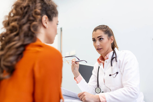 Young female professional doctor physician consulting patient, talking to adult woman client at medical checkup visit. diseases treatment. medical health care concept - Foto, imagen