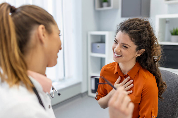 Νεαρή γυναίκα επαγγελματίας γιατρός συμβουλεύεται ασθενή, μιλώντας με πελάτη ενήλικης γυναίκας κατά την επίσκεψη ιατρικού ελέγχου. θεραπεία ασθενειών. ιατρική υγειονομική περίθαλψη έννοια - Φωτογραφία, εικόνα