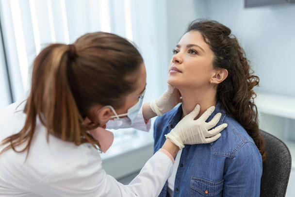 medicine, healthcare and medical exam concept - doctor or nurse checking patient's tonsils at hospital. Endocrinologist examining throat of young woman in clinic - Фото, зображення