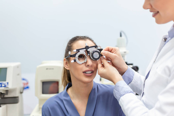 Oční zdraví cheking s oftalmologických přístrojů v laboratoři. Pomocí speciálního zařízení očnímu snaží zlepšit vidění Mladá krásná dívka. Práce s zdravotnické prostředky pro zdraví očí - Fotografie, Obrázek