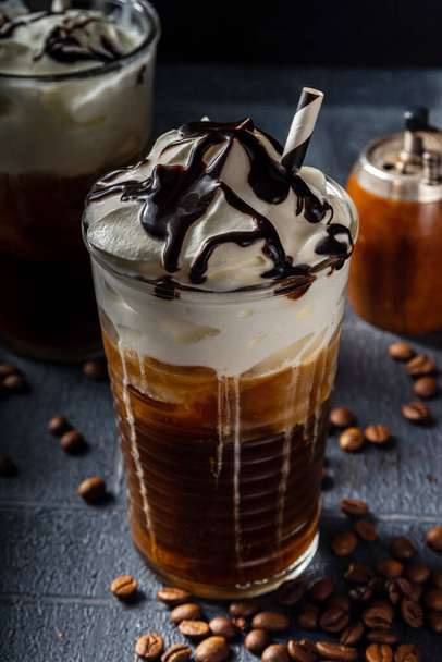 Cold coffee drink frappe (frappuccino), with whipped cream and chocolate syrup, with straws, coffee beans on a dark gray stone table, copy space  - Φωτογραφία, εικόνα