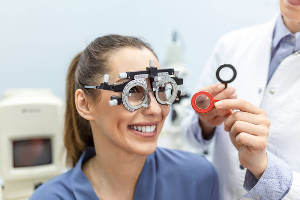 Офтальмолог вивчає жінку з оглядовою рамою. жіночий пацієнтка для перевірки зору в офтальмологічній клініці
. - Фото, зображення