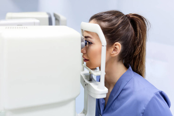 Test médical pour les yeux avec un appareil optique spécial dans la clinique moderne. Ophtalmologiste examinant les yeux d'un patient au microscope numérique lors d'un examen médical au cabinet ophtalmologique - Photo, image