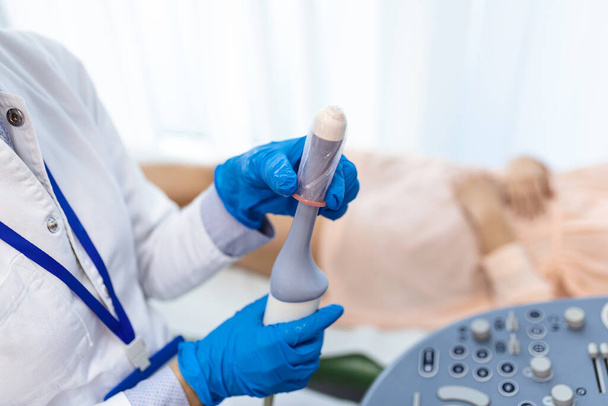 Le gynécologue place le couvercle de la sonde à ultrasons sur un scanner à ultrasons transvaginal pour l'examen vaginal d'une femme à l'aide d'une machine à ultrasons. Échographie des organes pelviens. Prise de vue rapprochée. - Photo, image