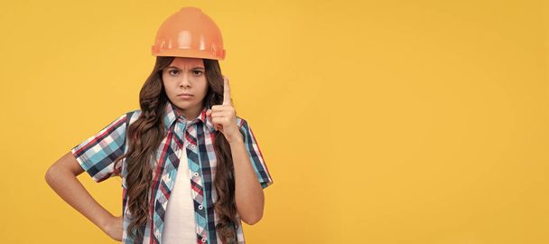 strict teen girl with curly hair in construction helmet, expert. Child builder in helmet horizontal poster design. Banner header, copy space - Photo, Image