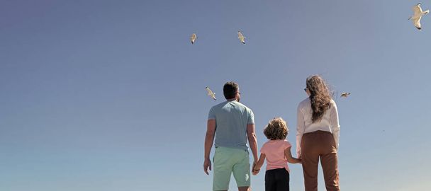 Знамя семьи, обнимающей на морском пляже. Летние семейные каникулы, горизонтальный баннер. Предыстория отпусков. Родители с мальчиком. Мама папа и сын любят расслабиться вместе. Страхование жизни - Фото, изображение