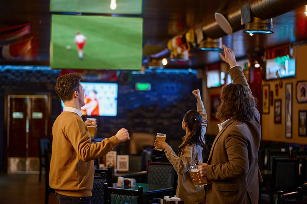 Mutlu futbol taraftarları bira içip spor barında futbol maçı çevirisini izliyorlar. - Fotoğraf, Görsel