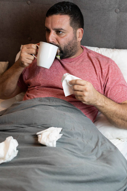 Мужчина средних лет в постели с симптомами гриппа - Фото, изображение