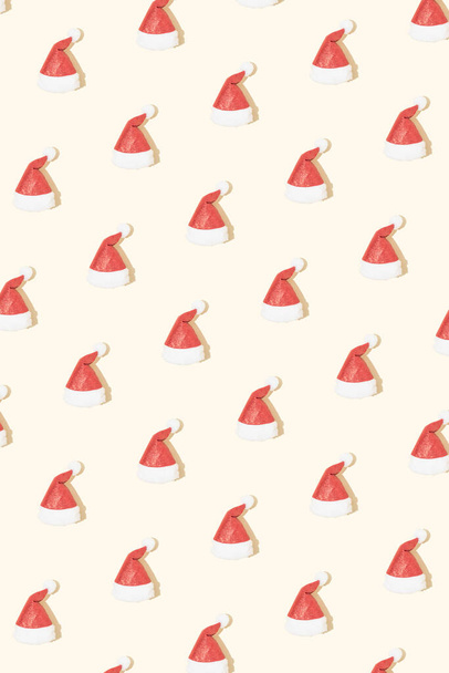 Christmas hats creative pattern. Santa Claus red hats on bright beige background. Minimal Christmas or New Year celebration concept. Trendy winter holidays layout. - Fotografie, Obrázek