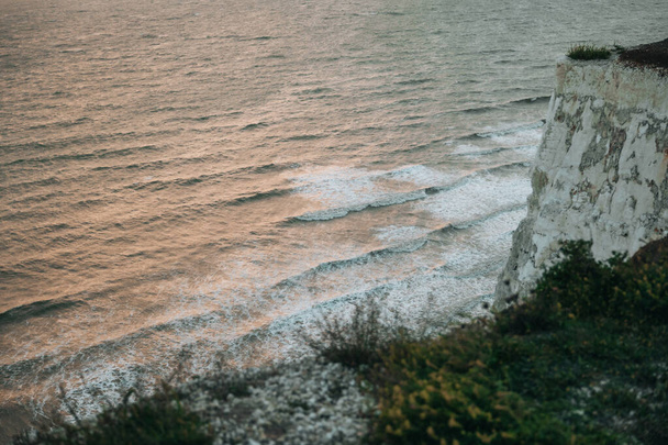 Vista de ángulo alto de las olas que golpean los acantilados de tiza de Seven Sisters, uno de los tramos más largos de costa subdesarrollada en la costa sur, East Sussex, Reino Unido. - Foto, imagen