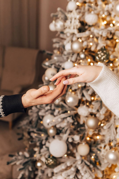 垂直画像素敵な若いロマンチックなカップル飾るクリスマスツリーキス巨大な居心地の良いインテリア雰囲気新年の休日パーティーコンセプト冬のガーランド夜を祝う - 写真・画像