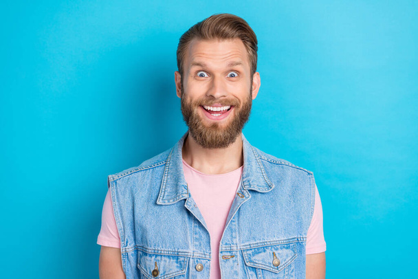 Photo of impressed excited young man wear jeans waistcoat smiling big eyes isolated blue color background. - Foto, Imagem