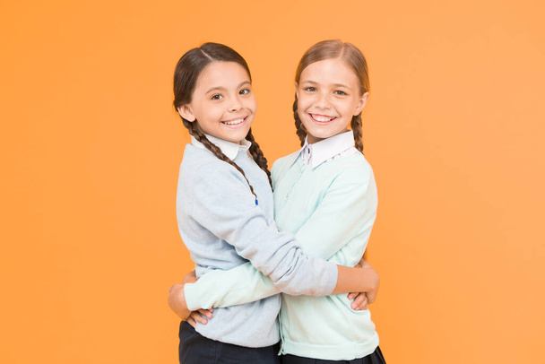 best friends. smart little girls on yellow background. education concept. back to school. knowledge day. childhood happiness. kid fashion. Friendship and sisterhood. happy girls in school uniform. - Foto, immagini