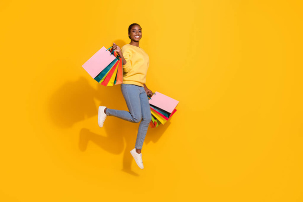 Full length body size view of attractive trendy cheerful girl jumping holding gifts black Friday isolated on bright yellow color background. - Zdjęcie, obraz