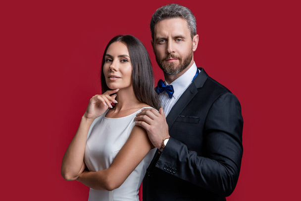 formal tuxedo couple of two isolated on red background. couple in formal tuxedo. studio shot of formal tuxedo couple. elegant couple wear formal tuxedo. - Foto, imagen