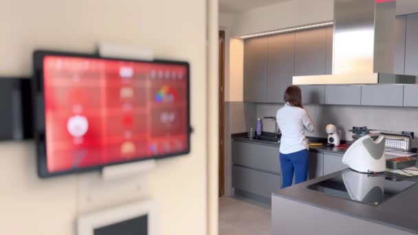 Smart Home Concept. Tableta muestra iconos de casa inteligente en un interior de la casa moderna con la mujer que trabaja en la cocina. - Metraje, vídeo