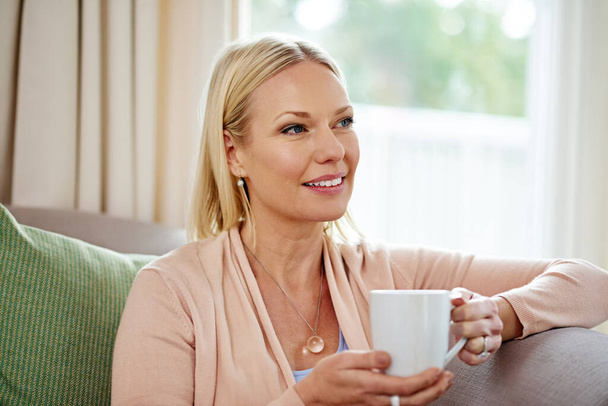 Αφήνοντας το μυαλό της να αναρωτιέται. μια ώριμη γυναίκα που δείχνει σκεπτική πίνοντας καφέ στο σπίτι - Φωτογραφία, εικόνα