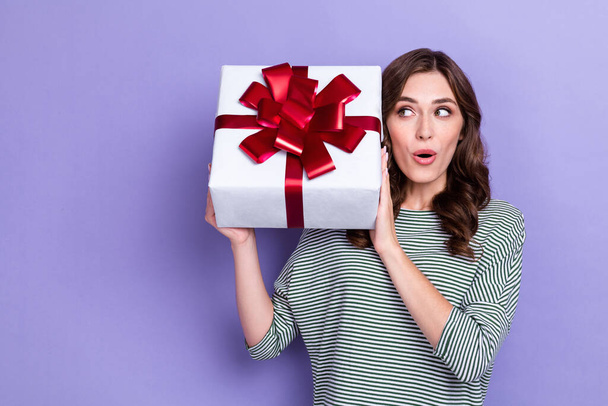 Photo of astonished lovely girlfriend lady hand hold present box listen interested look empty space isolated on purple color background. - 写真・画像