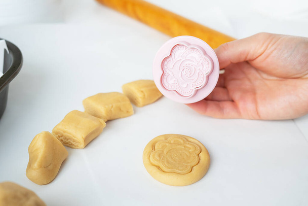 Η διαδικασία παρασκευής μπισκότων με σχήματα σε μορφή λουλουδιών, πλάστης και ταψιού, η έννοια του μαγειρέματος, το ψήσιμο στο σπίτι - Φωτογραφία, εικόνα
