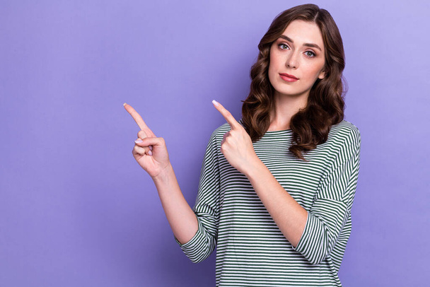 Photo of young charming cute confident woman serious face directing fingers mockup useful tips information isolated on pastel purple color background. - Foto, Imagem