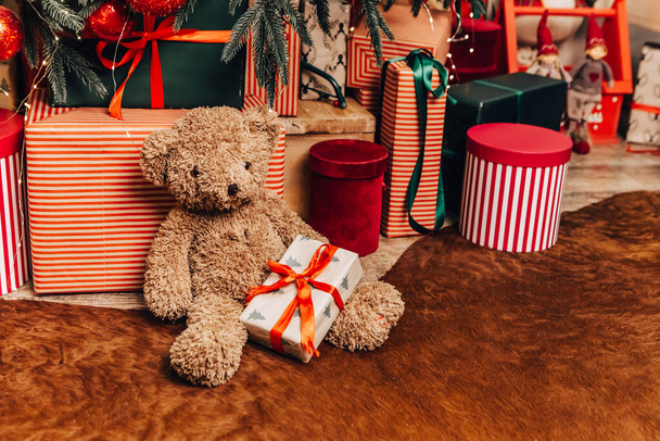居心地の良いフラットアパートの部屋緑のクリスマスツリーの贈り物は、ガーランド、キャンドル装飾されたおもちゃテディベアボールインテリア夜の美しいリビングルーム、光輝くボケ - 写真・画像