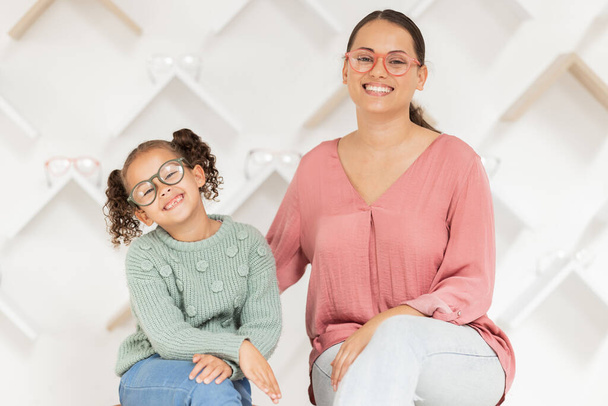 Family, eye care and glasses on mother and child in optics store for shopping, optometry and health care while advertising lens or frame choice. Portrait of woman and girl happy with vision insurance. - Фото, изображение