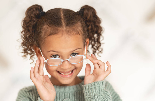 glasses, child face and eye care for vision in optometrist office. Excired young girl, happy and smile for eye exam, eyes healthcare treatment and optometry lens fashion portrait for wellness support. - Photo, Image