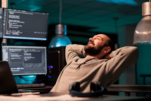 Happy relaxed developer sitting laid back on chair, feeling pleased about software development work in office. Enjoying server programming success late at night, server code html script. - Fotografie, Obrázek