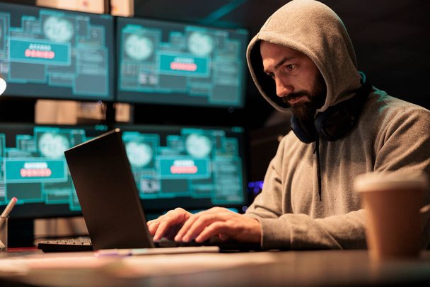 若い男は、コンピュータに感染し、ビッグデータを盗むためにウイルスを使用して、インターフェイスのセキュリティを破るためにパスワードをハッキング。システムデータベースへのサイバー攻撃を行う危険な謎のハッカー、 IT詐欺. - 写真・画像