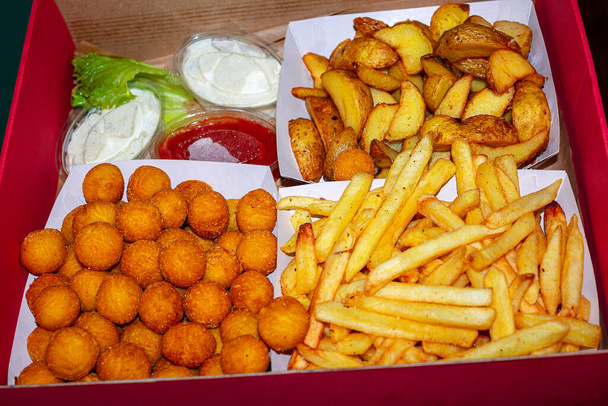 Картопляна коробка з кульковою картоплею та картопляними клинами та часниковим соусом
 - Фото, зображення