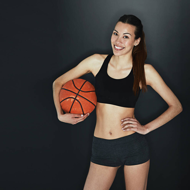 Find your greatness. Studio shot of a young woman holding a basketball against a dark background - Foto, Imagen