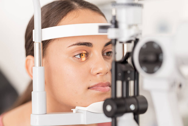 Healthcare, eyes and woman eye test at a clinic for vision, health and eyesight on a slit lamp examination. Face, eye care and girl consulting optometrist for sight, wellness and glaucoma testing. - Photo, Image