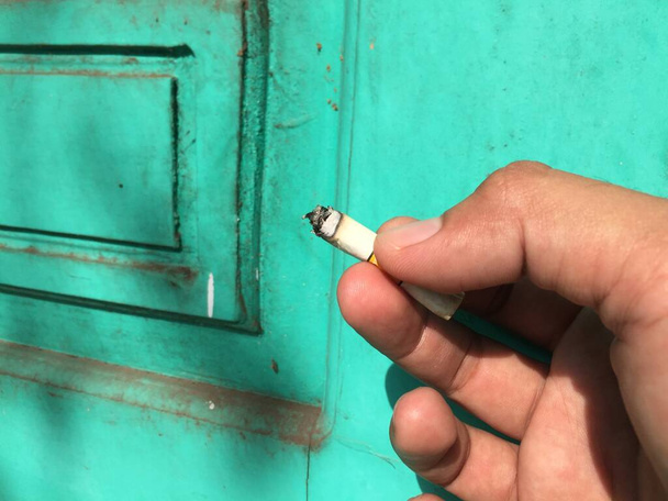 mão segurando um cigarro que está prestes a acabar - Foto, Imagem