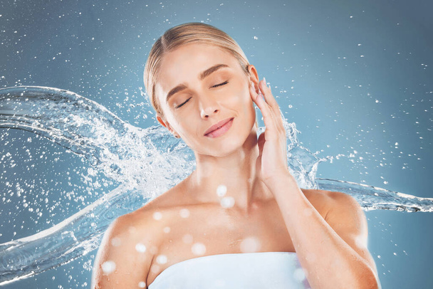 Water splash, woman and beauty on blue background of skincare, aesthetic wellness or clean body care, shower or personal hygiene. Young studio model in wet bathroom, water stream or natural cosmetics. - Fotografie, Obrázek