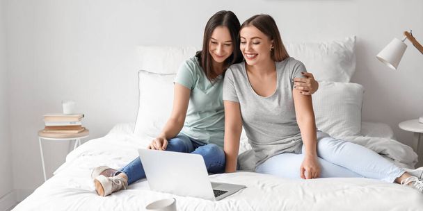 Junge lesbische Paare mit Laptop im Schlafzimmer - Foto, Bild