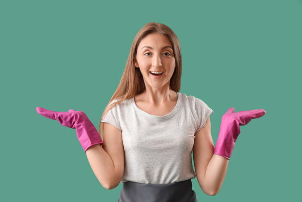 gelukkig jong vrouw met rubber handschoenen op groene achtergrond - Foto, afbeelding