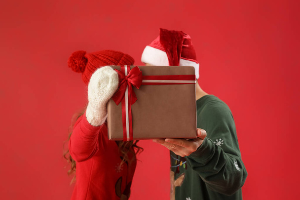 Giovane coppia innamorata del regalo di Natale su sfondo rosso - Foto, immagini