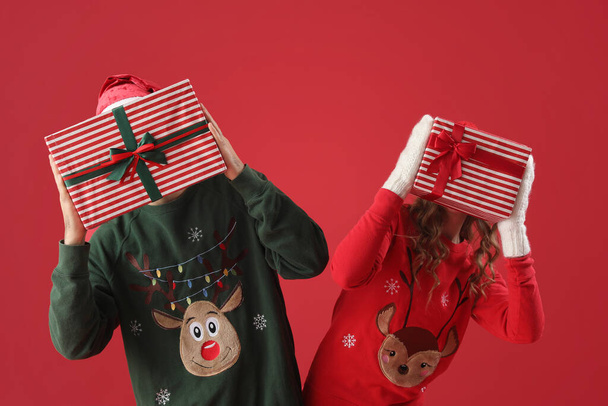 Молодая пара влюблена в рождественские подарки на красном фоне - Фото, изображение