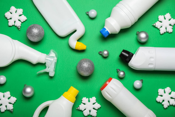 Bottles of detergent with Christmas balls and snowflakes on green background - Фото, зображення