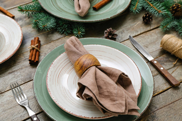 Beautiful table setting with Christmas branches, fir cones and cinnamon on wooden background, closeup - Foto, afbeelding