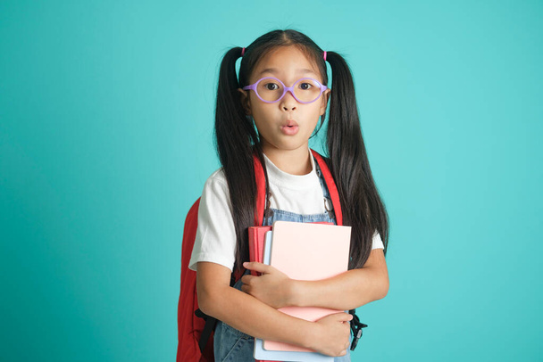 Közelkép iskolás lány szemüveget visel, ő szép aranyos vonzó vonzó vidám csodálkozik, engedetlen gyermek szórakozik. elszigetelt kék pasztell háttér.Oktatási koncepció az iskola - Fotó, kép