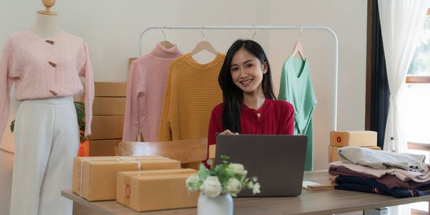 Start-up Kleinunternehmer von freiberuflichen asiatischen Frau mit einem Laptop mit Box Fröhlicher Erfolg Online-Marketing Verpackungsbox und Lieferung KMU-Idee Konzept. - Foto, Bild