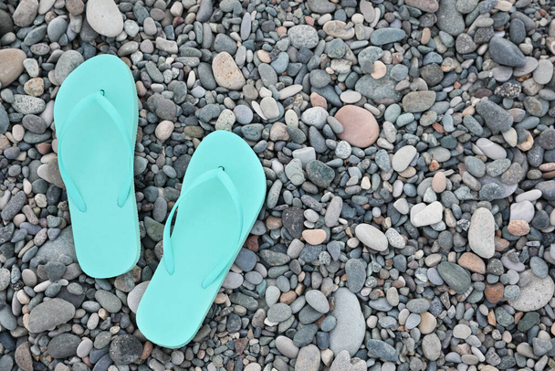 Stylish turquoise flip flops on pebble seashore, top view. Space for text - Foto, Imagem