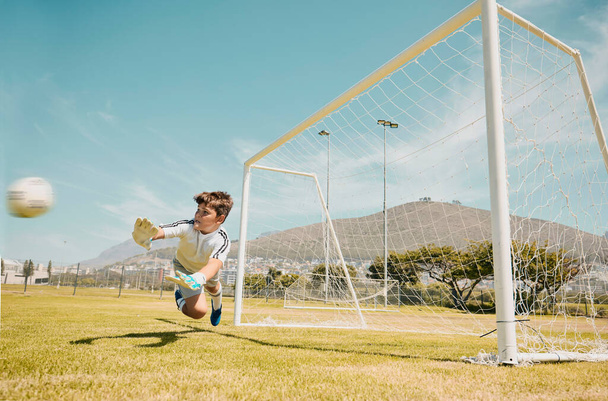 ゴールキーパーを持つサッカー、スポーツ、子供たちは、芝生のピッチやフィールドでの競争力のあるゲーム中にショットを保存します。サッカー、子供たちと得点からボールを保存または停止する男性の子供のダイビングと目標. - 写真・画像