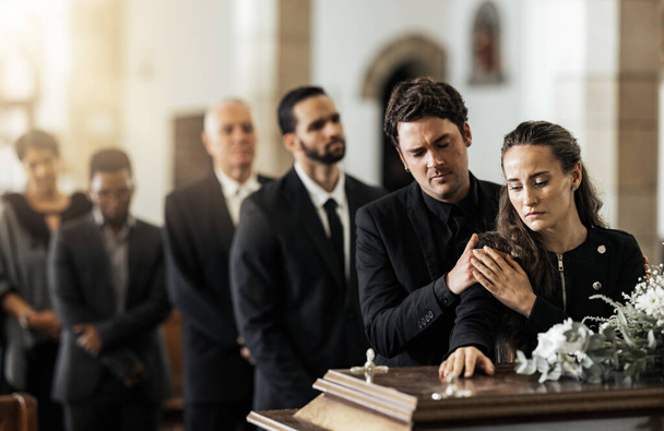 Θάνατος, κηδεία και οικογένεια αγγίζουν το φέρετρο σε μια εκκλησία, λυπημένοι και δυστυχισμένοι ενώ μαζεύονται για να πουν αντίο. Εκκλησία κηδεία φέρετρο και λυπημένος άντρας και γυναίκα αναζητούν αναστατωμένος, ενώ χαιρετισμό, αντίο και rip. - Φωτογραφία, εικόνα