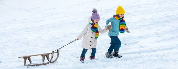 Winter children with sled. Active winter outdoors games. Happy kids friends on winter vacation - Foto, afbeelding