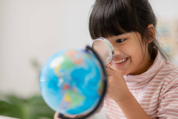 Ασιατικό κοριτσάκι μαθαίνει το μοντέλο κόσμο, έννοια της σώσει τον κόσμο και να μάθουν μέσα από το παιχνίδι δραστηριότητα για την εκπαίδευση των παιδιών στο σπίτι. - Φωτογραφία, εικόνα