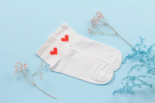 Pair of white women socks and decorative branches on the blue background, Top view. - Fotografie, Obrázek