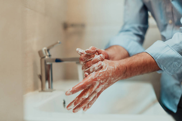 Man using soap and washing hands under the water tap. Hygiene concept hand closeup detail. High quality photo - Zdjęcie, obraz